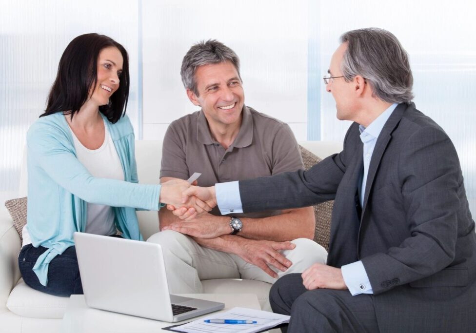 A man and woman shaking hands with an older gentleman.