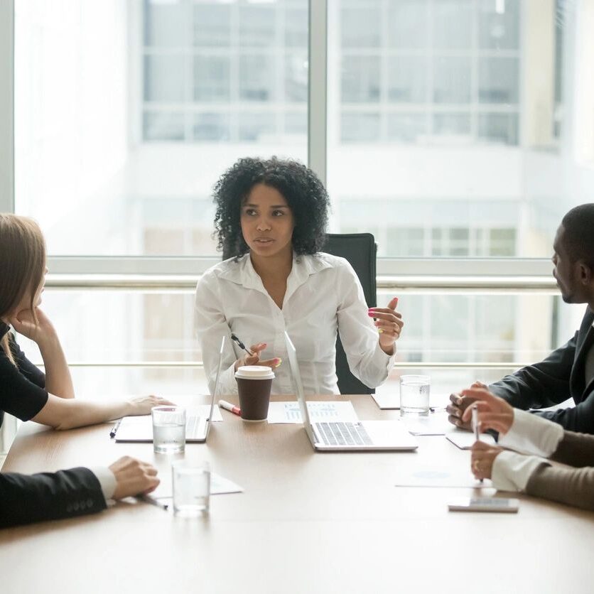 A group of people sitting at a table in front of a window.