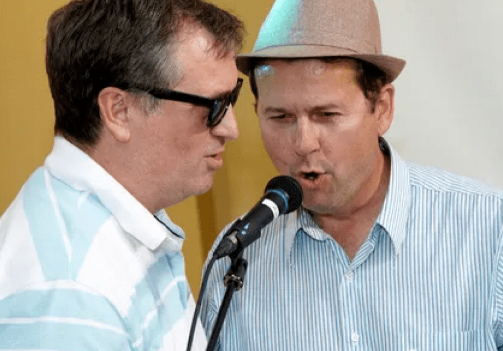 Two men singing into a microphone.