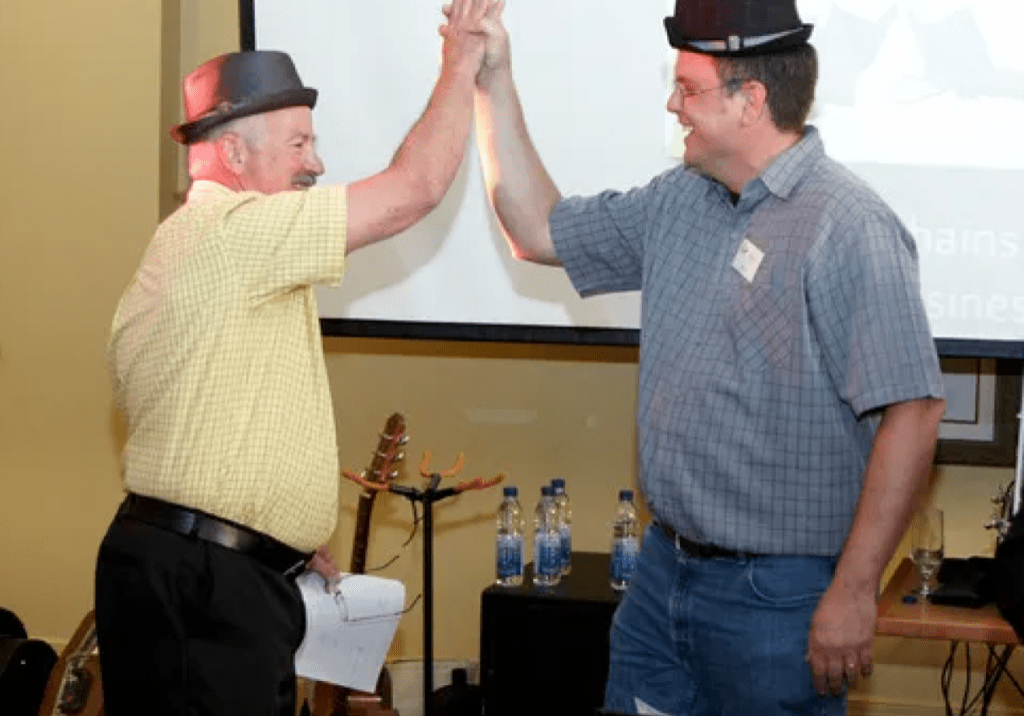 Two men high-fiving in hats.